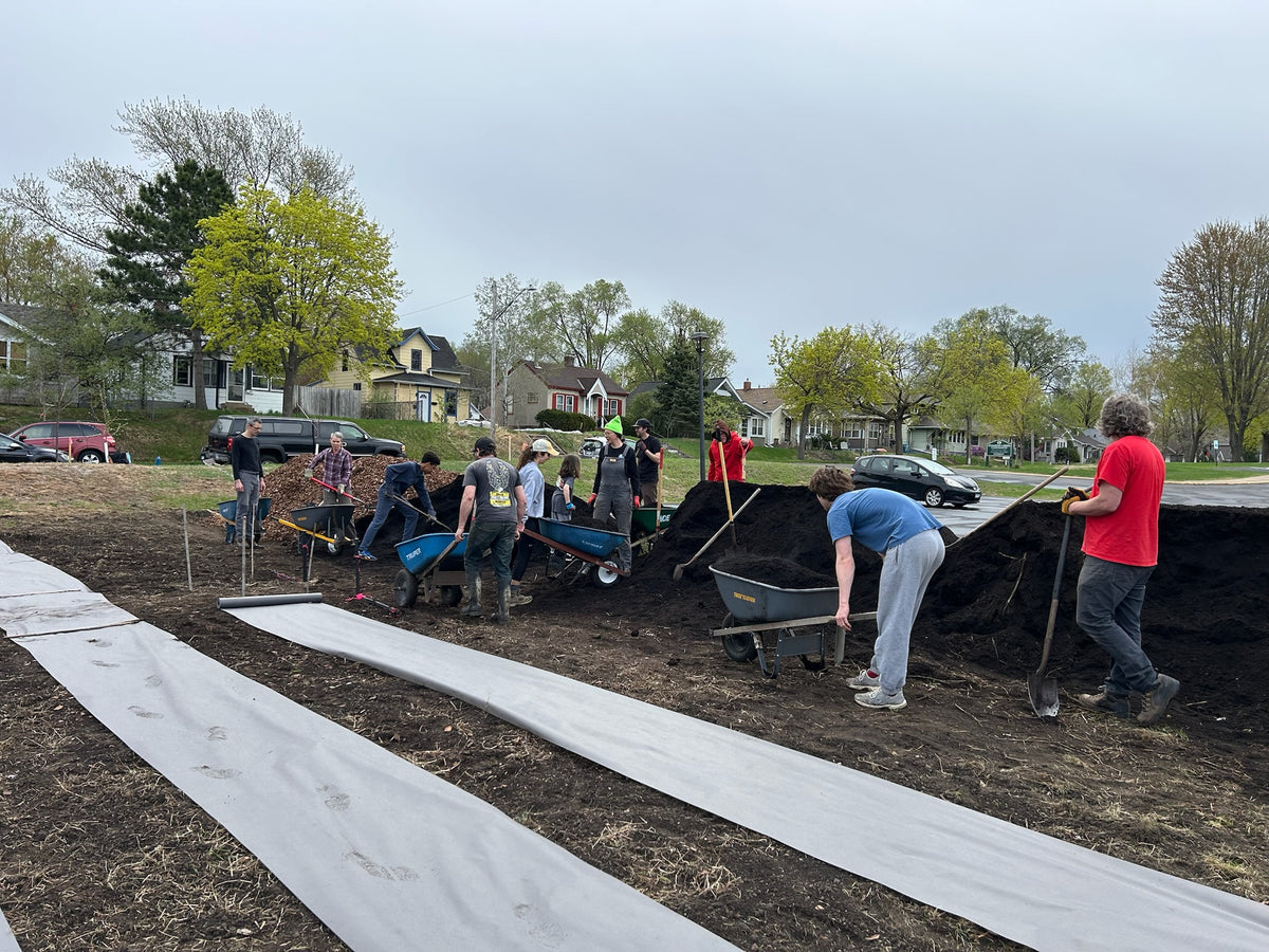 Group of people working with wheelbarrows and shovels to build The Black Radish Urban Farm in Minneapolis.